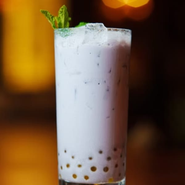 A tall glass of Fulin's Asian Cuisine's taro bubble tea, garnished with mint, against a warm background.