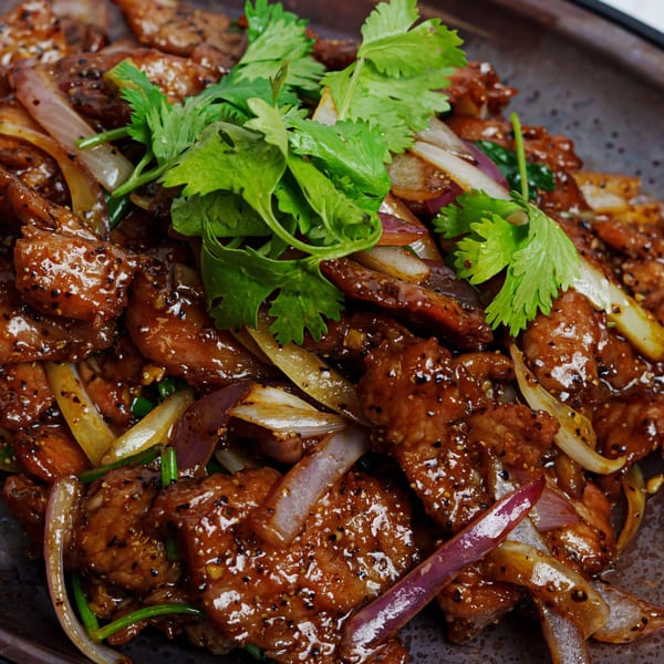 Fulin's Asian Cuisine's Chinese black pepper beef with onions and cilantro on a dark plate.